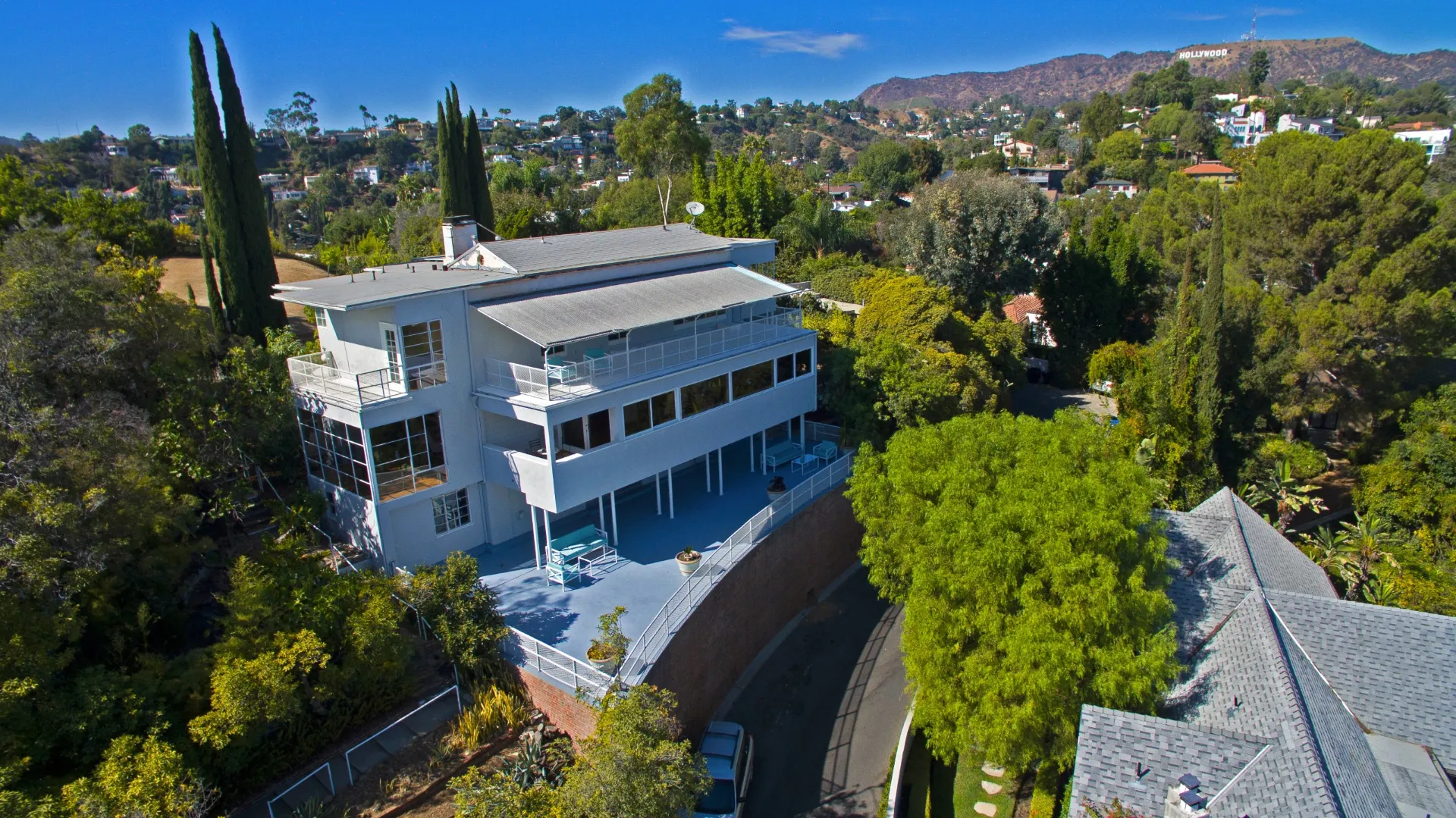 Aerial view of a modern hillside home with the Hollywood Sign in the distance